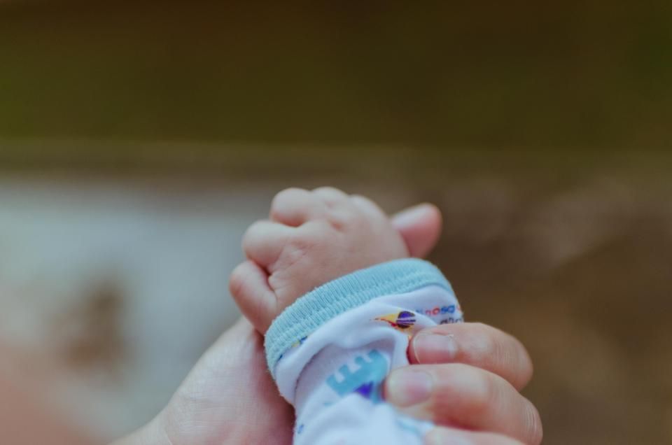 Manos de una persona adulta sosteniendo la mano de un bebé