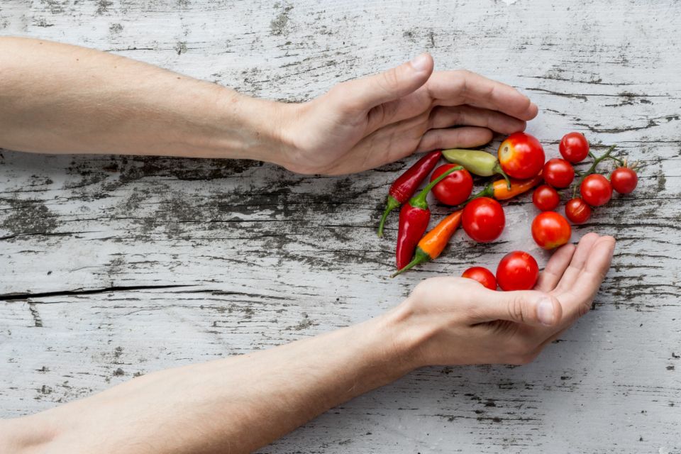 Manos sosteniendo tomates cherry sobre una mesa de madera